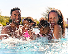 Photo of a family of four playing in the pool.