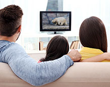 Photo of a family watching television in their living room.