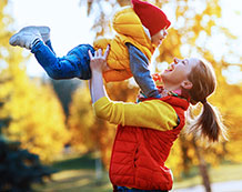 Photo of a mother and child smiling and playing outside.