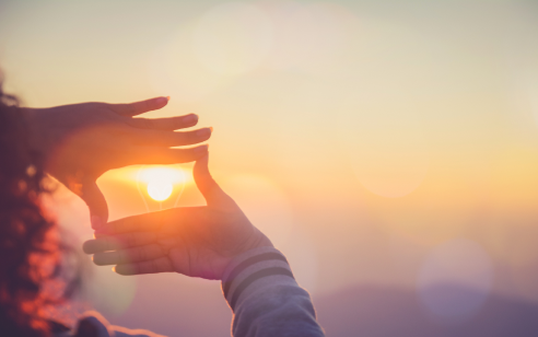Woman framing sun with hands