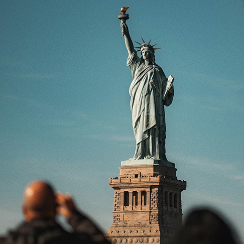 Image Description: A traveller snapping a photograph of the Statue of Liberty
