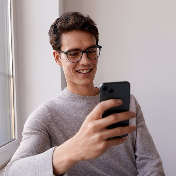 Hier ist ein Mann mit einem Handy und Brille zu sehen.