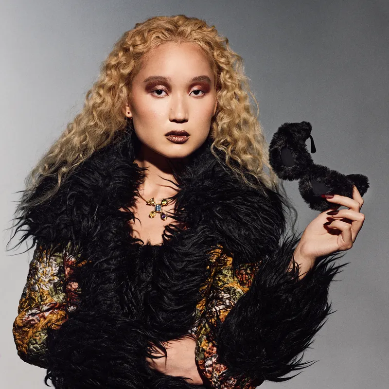 beautiful model with blonde curly hair wearing dark red manicure and fuzzy black jacket
