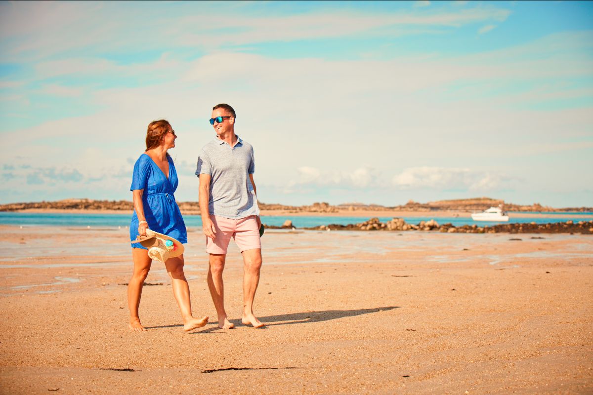 Couple walking on shell beach, Herm