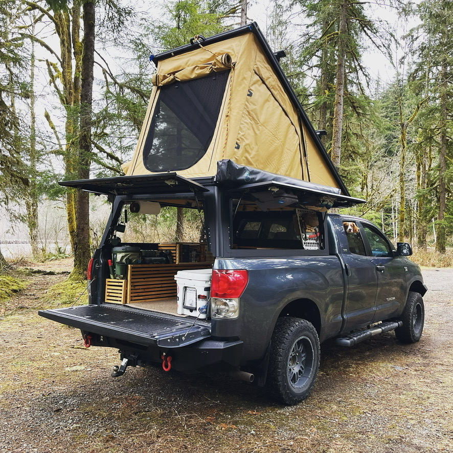 An X1 Camper on the back of a Toyota Tundra truck in the woods.