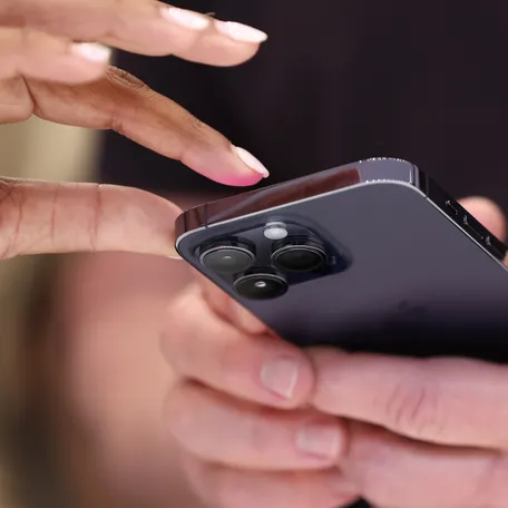 A person is pictured holding an iPhone.