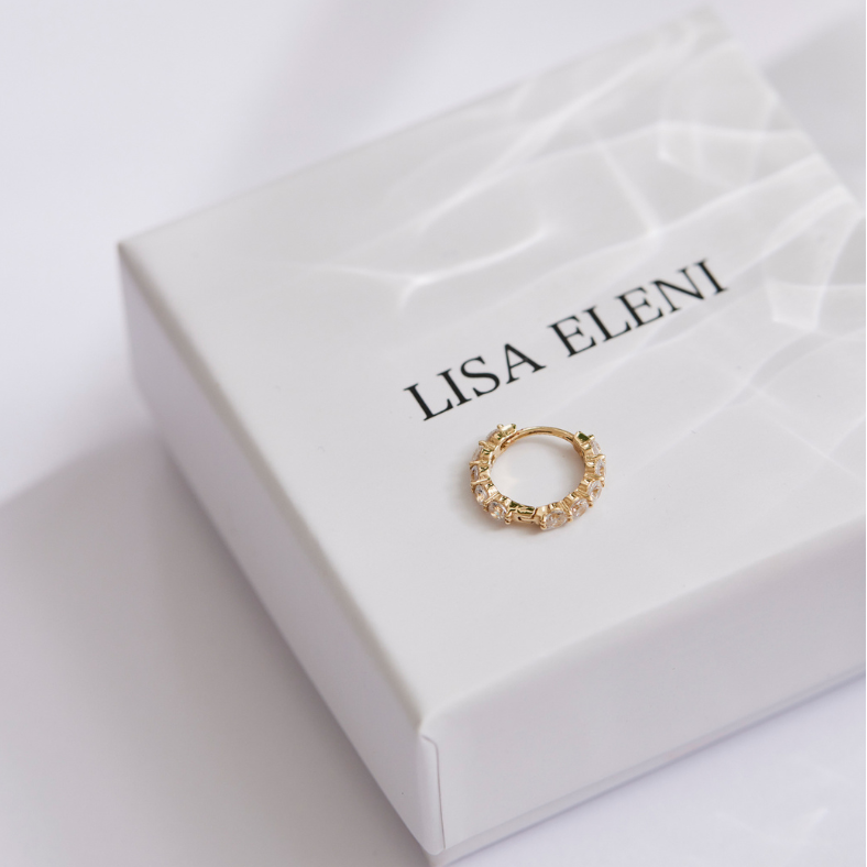 Eine Gold Creole liegt auf einer Schmuckschachtel von Lisa Eleni