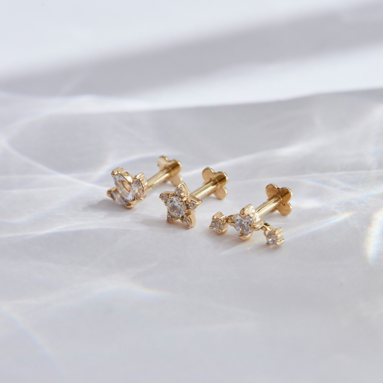 Gelbgold Ohrstecker liegen auf einer grauen Fläche
