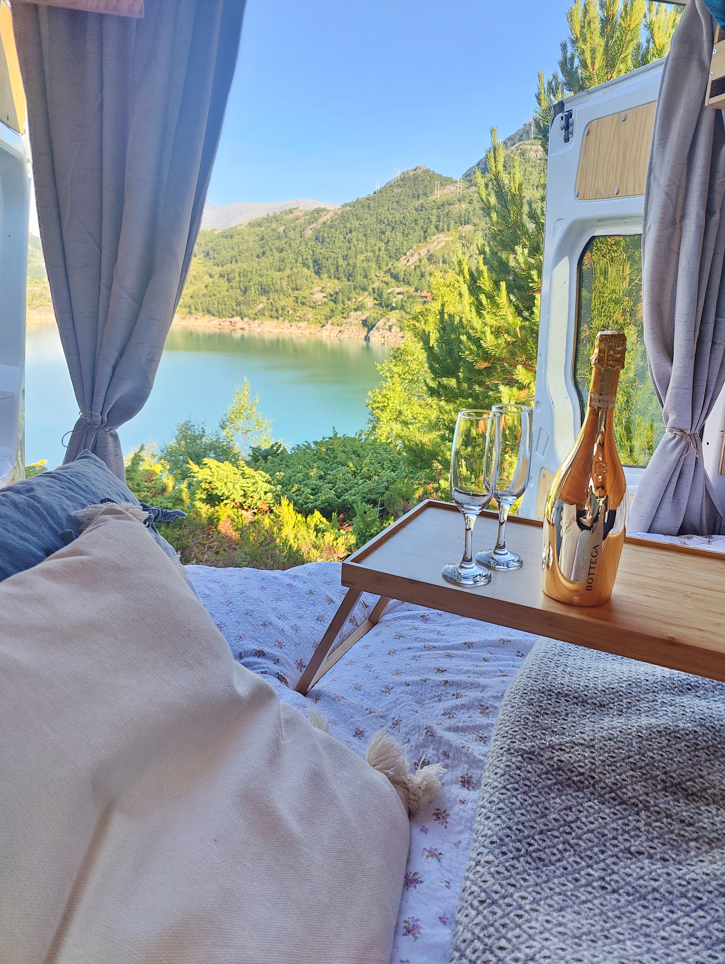 a campervan with a bed and a bottle of wine on a table
