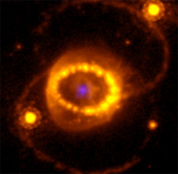 A small blue dot (the neutron star) is surrounded by an oval halo of blurry orange glowing lights, from which two faint spiral arms emerge linking single bright dots 