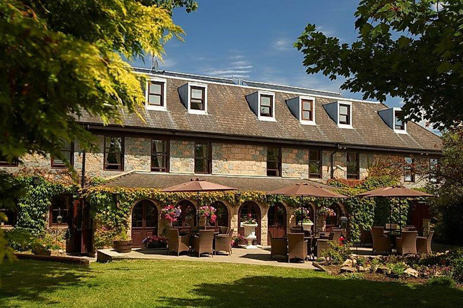 exterior of le friquet hotel from the gardens with trees and flowers