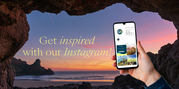 hand holding mobile phone showing our instagram account against a sunrise picture of a guernsey beach