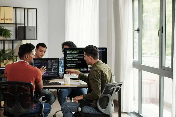 Software engineers and developers discussing programming code and planning how to create innovative software system life cycle that adheres to ISO/IEC/IEEE 15288:2023. 