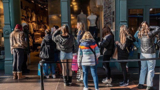 Shoppers wait in line on the sidewalk outside a Brandy Melville store