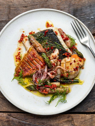 A plate of pan-cooked asparagus & seafood  with a fork next to it