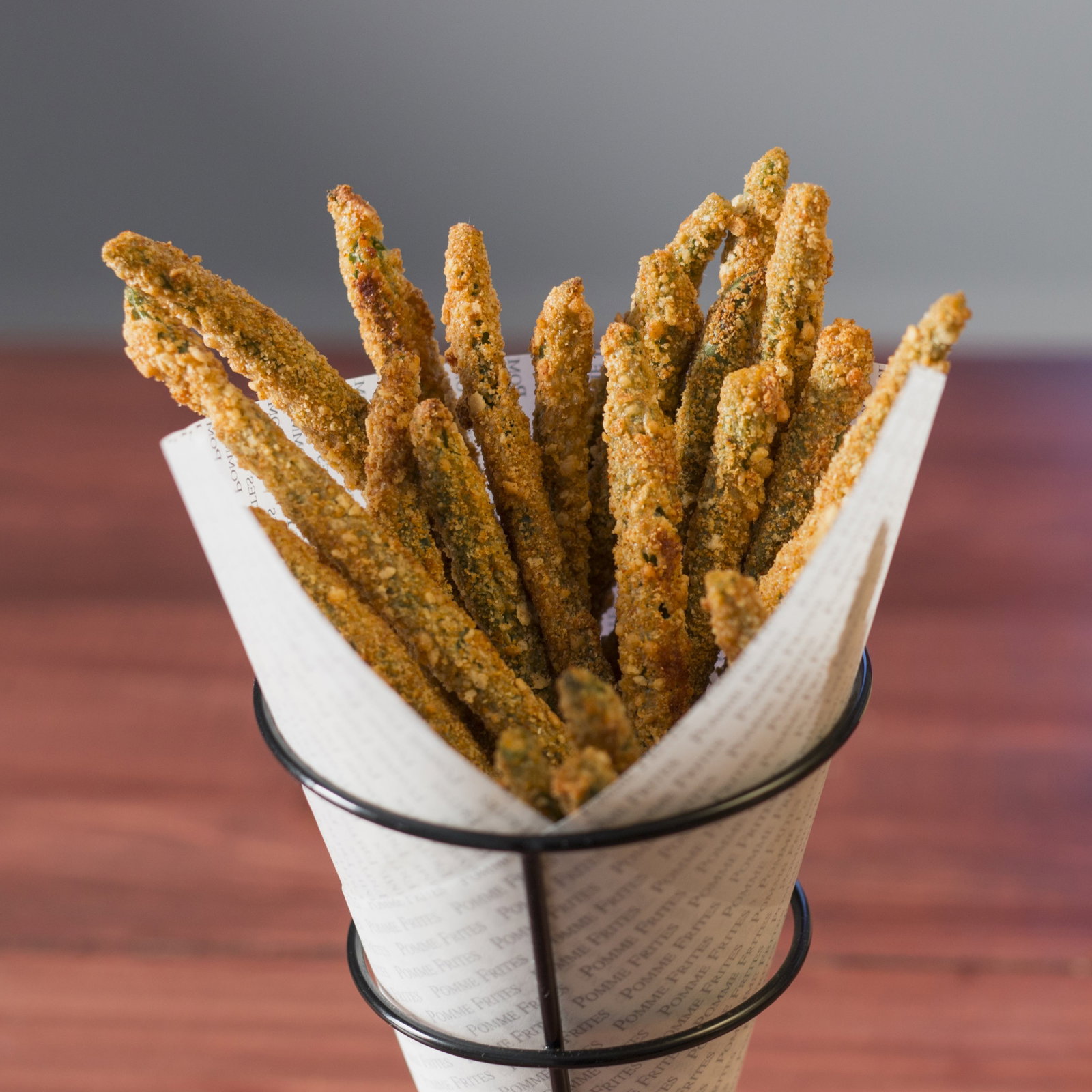 a basket of baked green bean fries resembling french fries sitting on a table