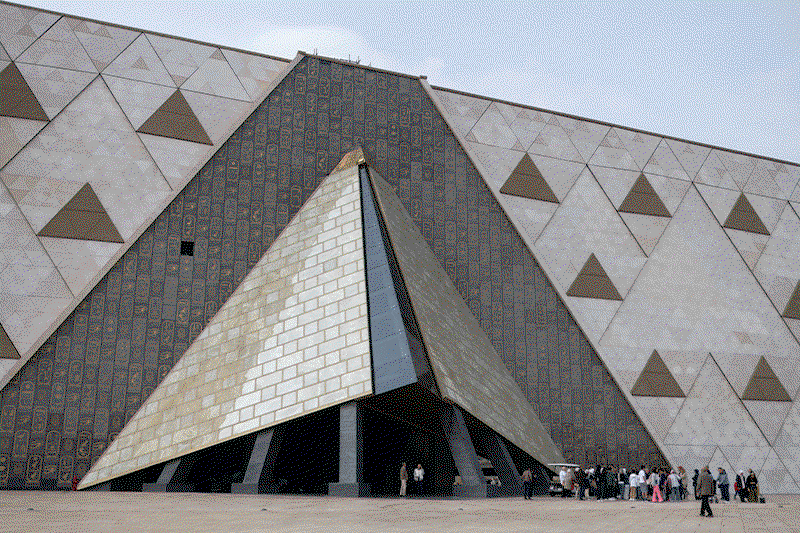 Animated sequence of four photos including images of the Grand Egyptian Museum exterior, the Grand Staircase, a statue of Ramses II in the lobby and a large vehicle transporting the first Khufu boat to the museum in 2021.