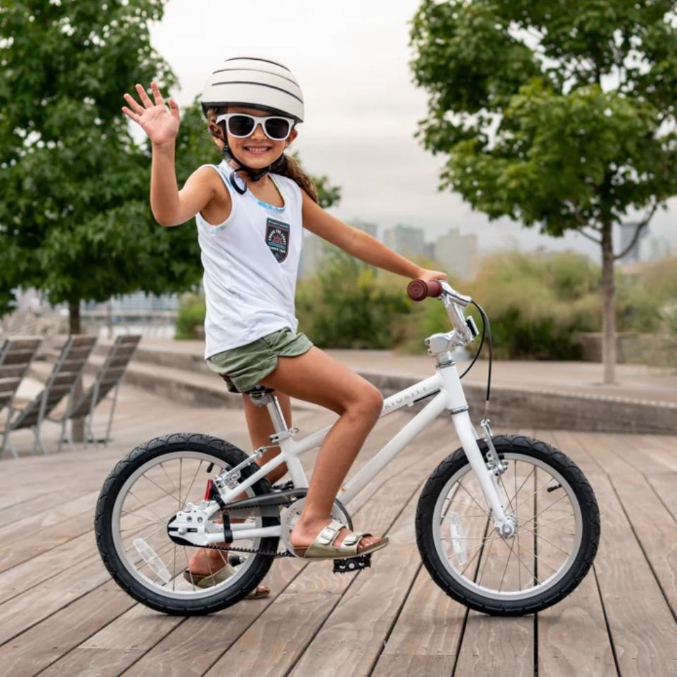 Kid riding a white Priority Start 16 bicycle