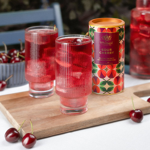 Sour Cherry Instant Tea on a Picnic Table with tall glasses of tea. Cherries lie on the table