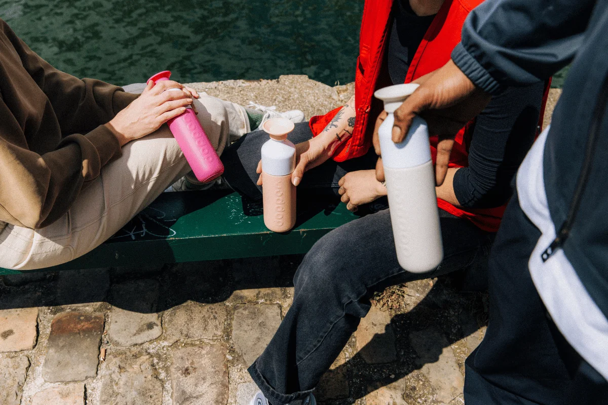 Three people each holding a Dopper Insulated bottle