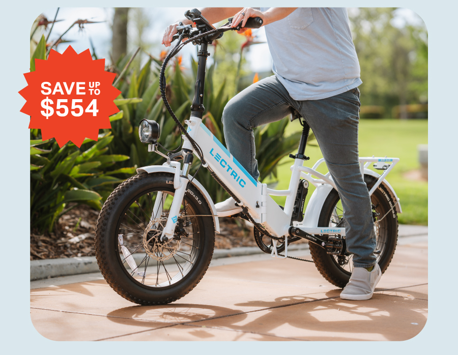 man riding XP 3.0 white step-thru ebike through park on the way to a tailgate