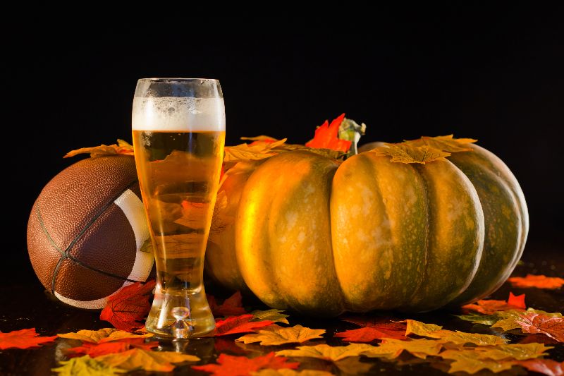 glass of beer with pumpkin and football