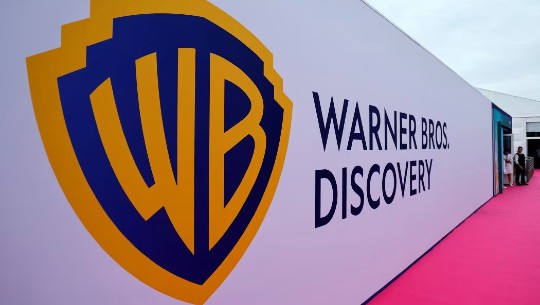 The Warner Bros. Discovery logo and name on a long white wall