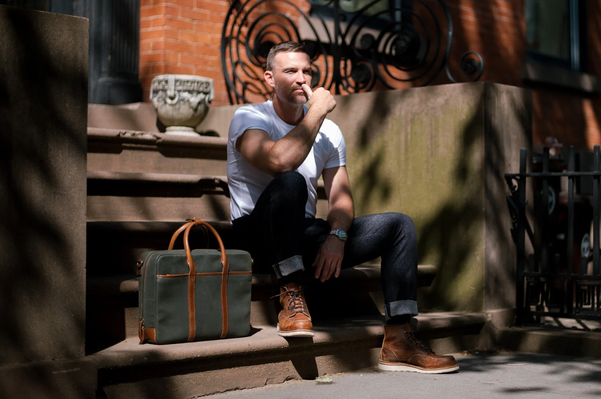 man walking outside carrying leather bag