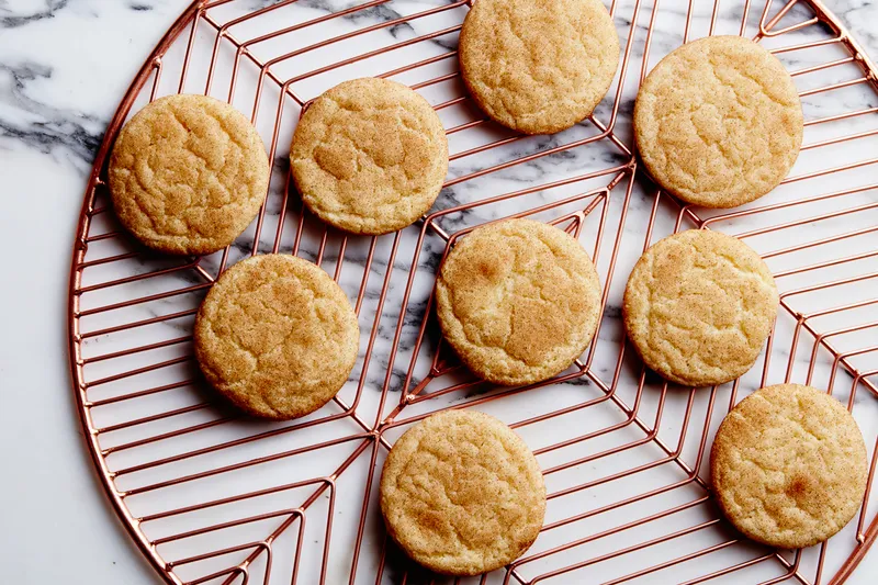 9 snickerdoodles on a rose gold cooling rack.