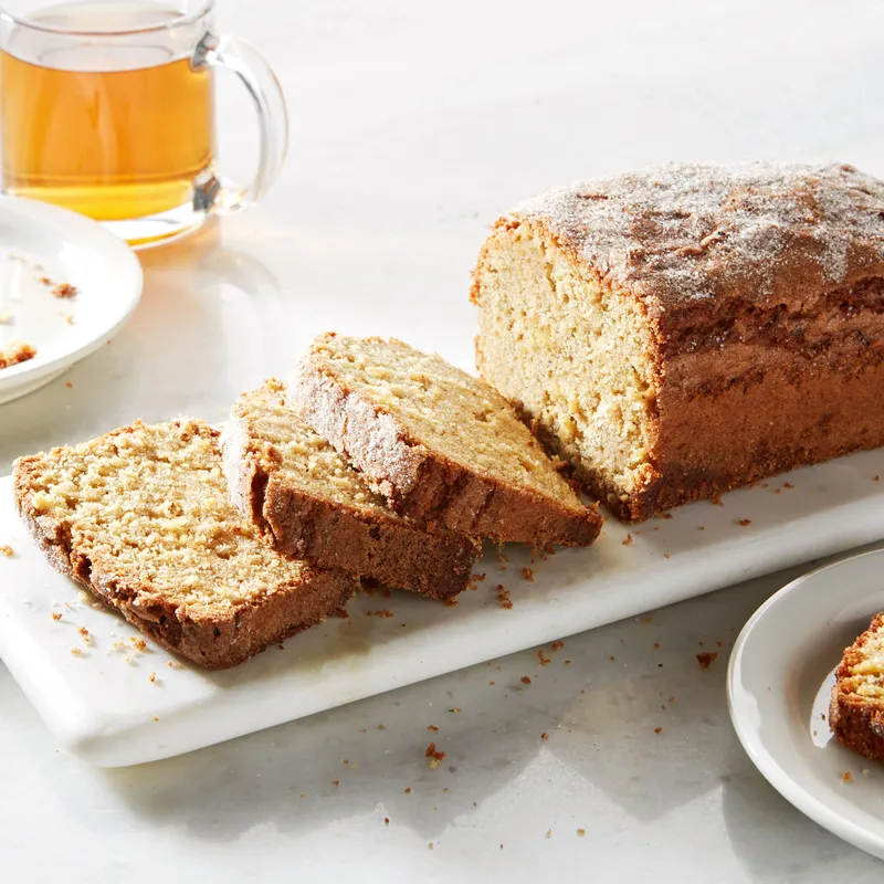 Sliced loaf of apple olive oil cake on a white tray. 