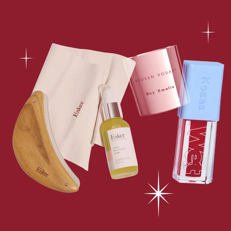 Best Bluemercury gifts. Overlapping cosmetic products on a dark red background with white sparkles.