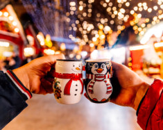 Deux personnes trinquent avec des mugs dans un marché de Noël