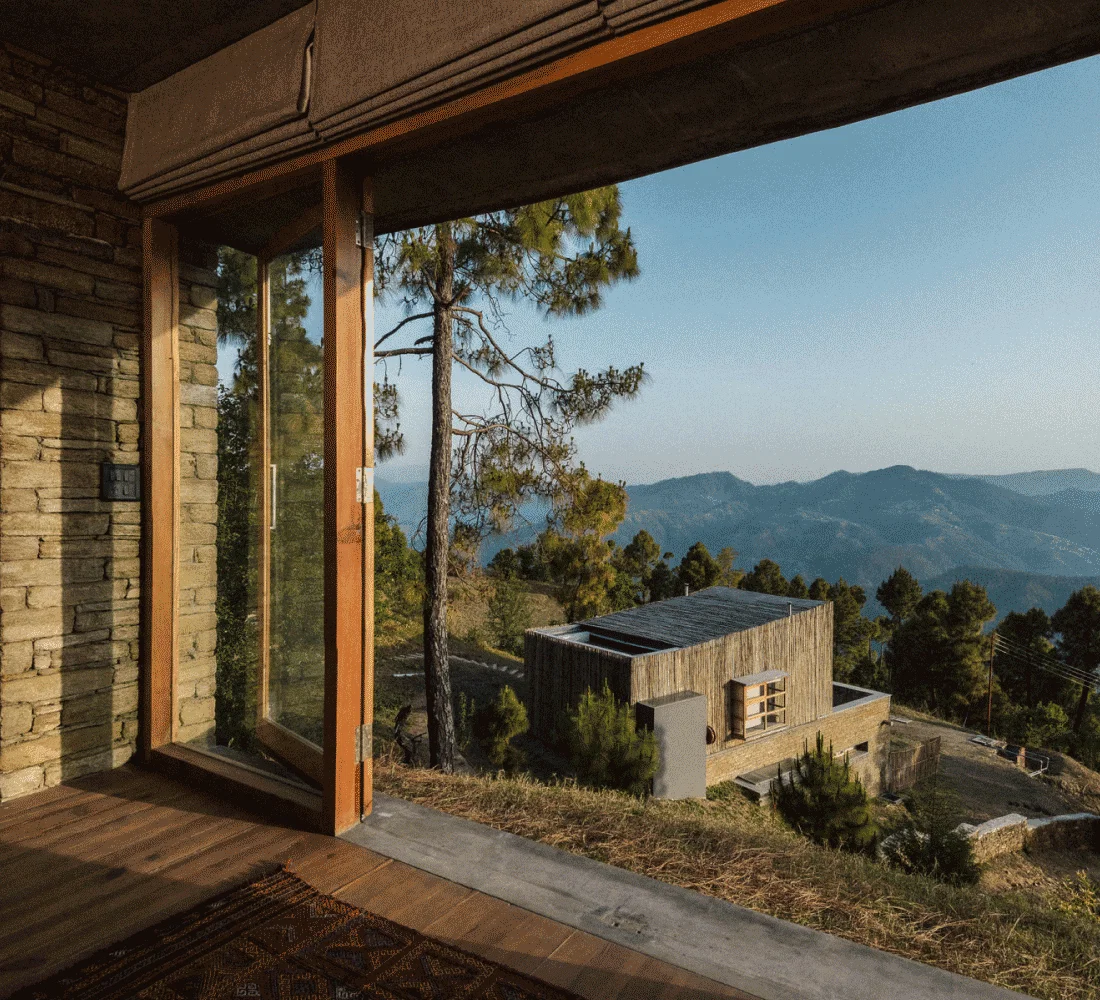 Image Description: Sweeping views of the Himalayas and lush forests from a chalet in The Kumaon, a luxe mountain retreat in India
