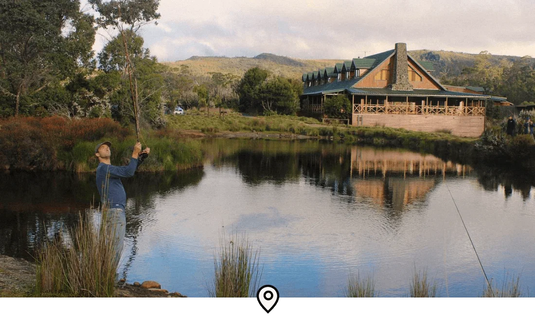 Image Description: A traveler fishing at the lake in front of Peppers Cradle Mountain Lodge in Tasmania, Australia
