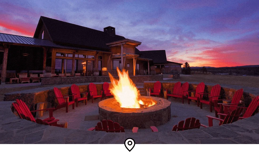 Image Description: A wood-burning fire pit surrounded by red patio chairs at Brasada Ranch, a resort in Powell Butte, Oregon
