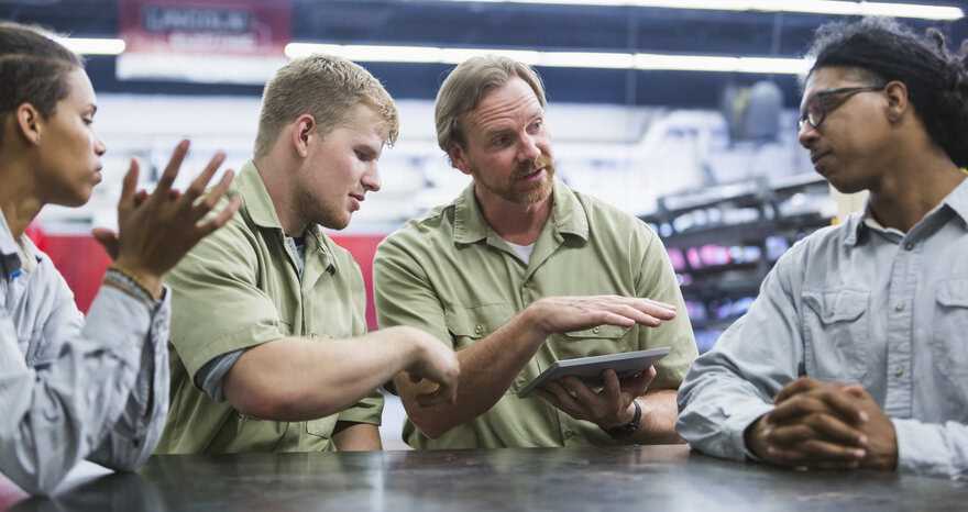 Teacher working with technical students in factory to conduct ANSI/ASSP Z490.1-2024 SH&E training.