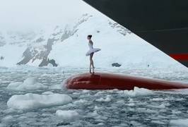 Ballerina danst op boeg van schip tussen ijs bij Antarctica