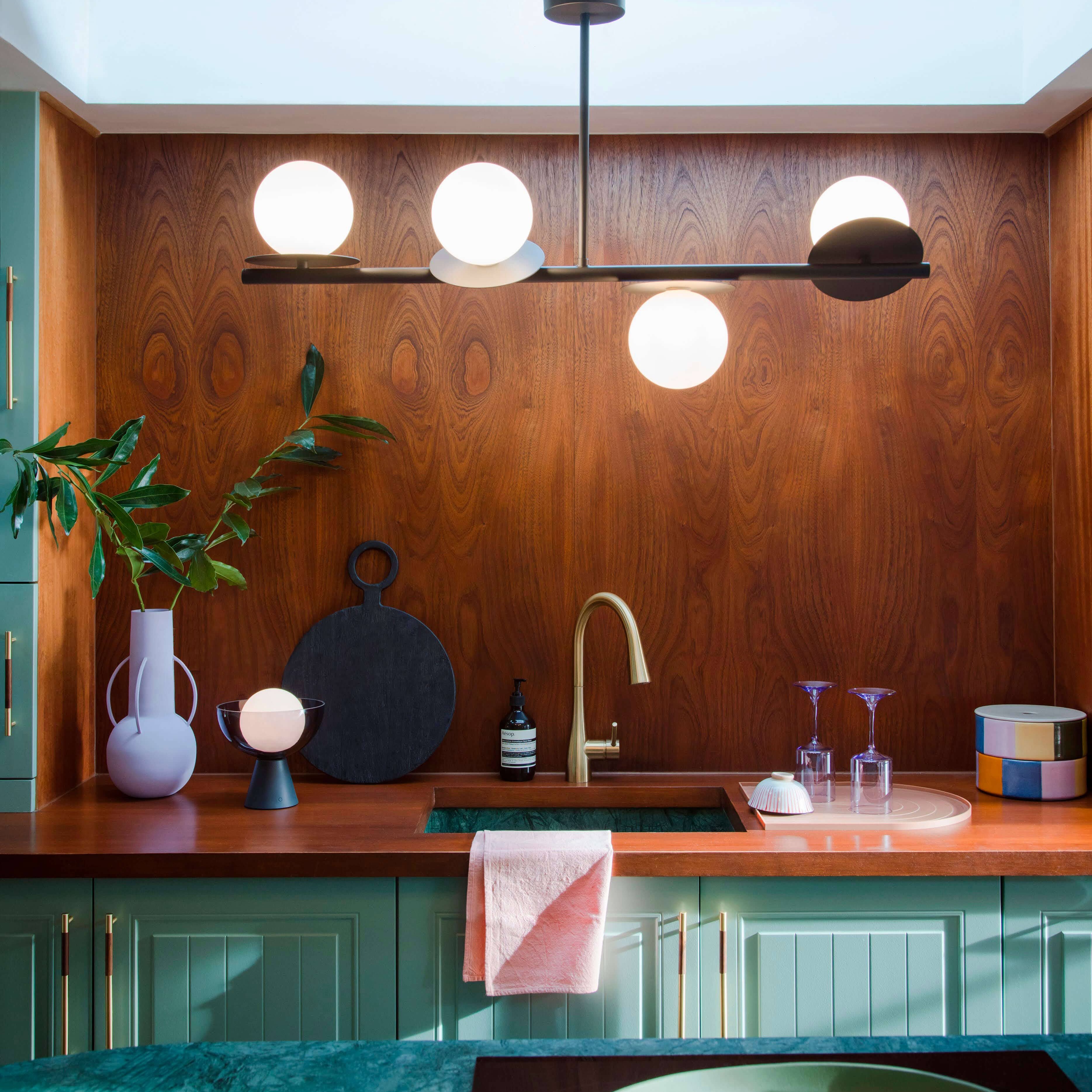 Grey bar kitchen light with 4 bulbs hung over a sink in a green kitchen
