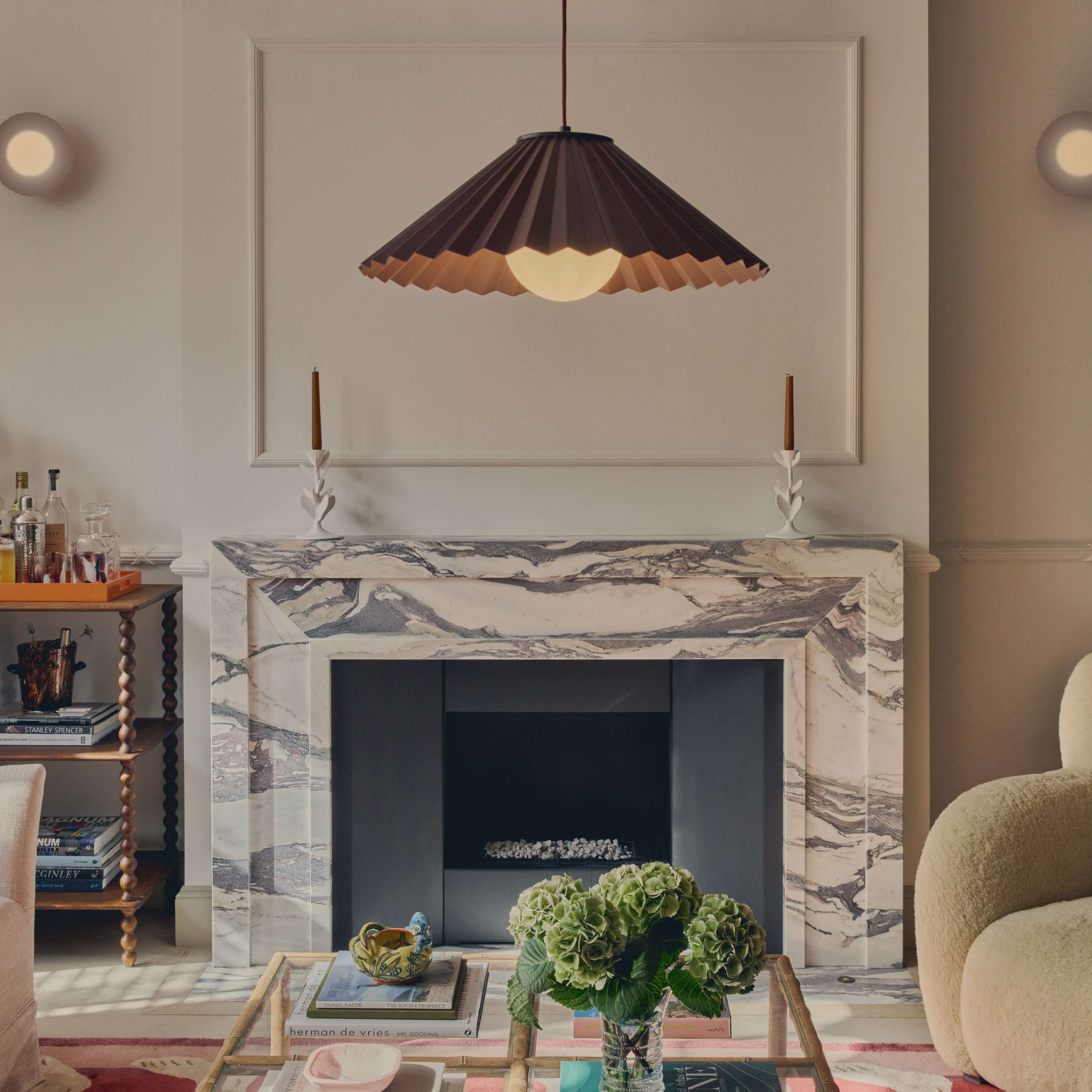 Living room with marble fireplace, sofa and chair with a burgundy light in the middle.  Two wall lights which match are on either side of the fireplace