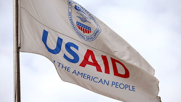 A flag displaying the logo for the US Agency for International Development (USAID) outside of its headquarters in Washington, DC.
