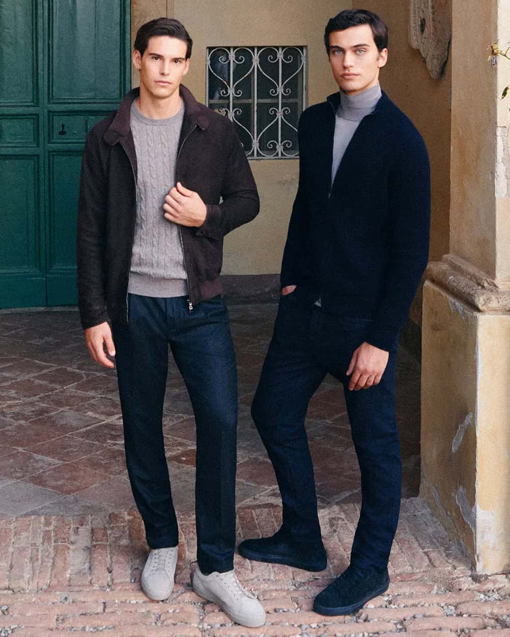 two men standing next to each other in front of a building