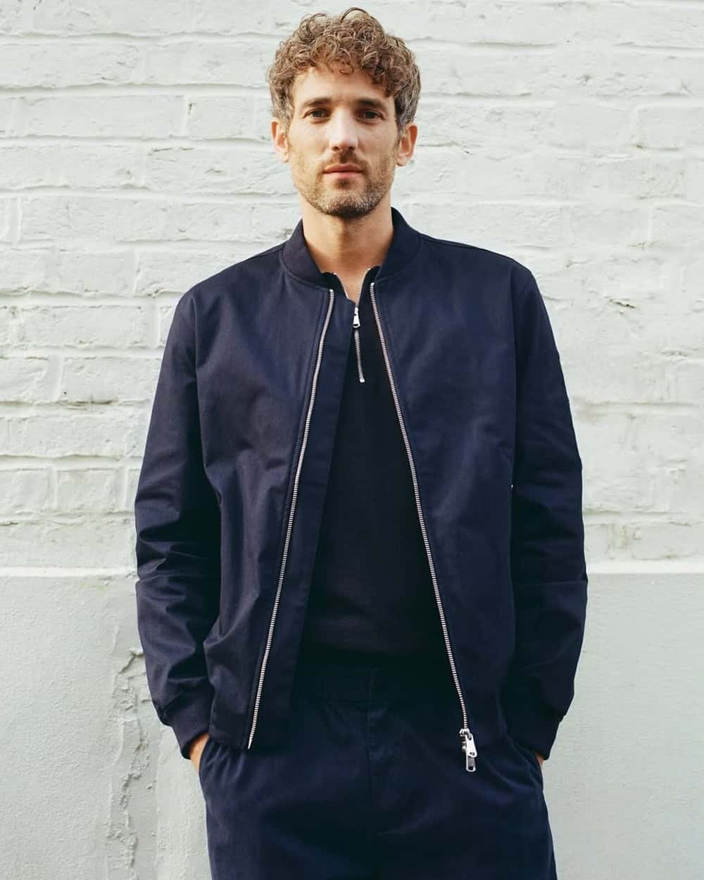 a man wearing a blue bomber jacket with his zipper open