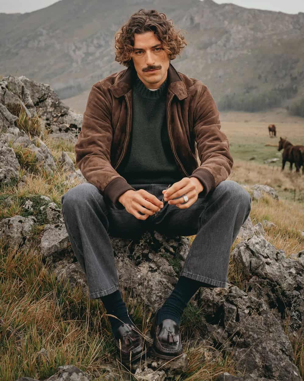 a man sitting on a rock in a field