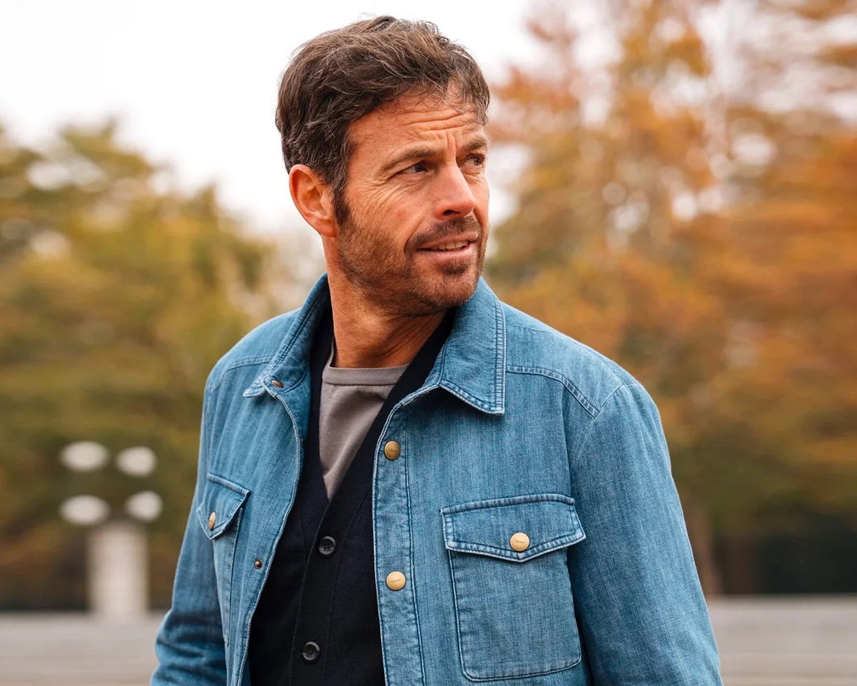 a man wearing a denim jacket and looking off into the distance