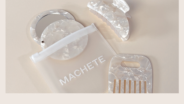 A photograph of a 3-piece collection of hair accessories including a mirror, comb, and clip, arranged with a branded pouch labeled "MACHETE."