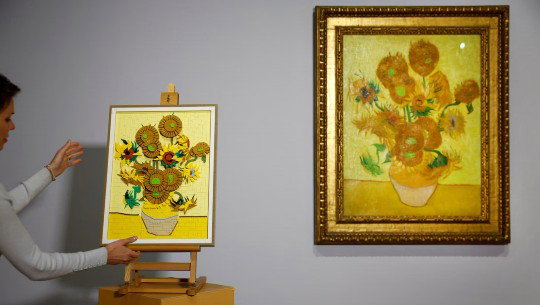 A Lego kit depicting Van Gogh’s Sunflowers next to the original