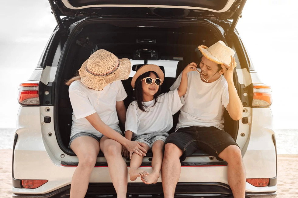Family sitting in the trunk of their SUV at the beach