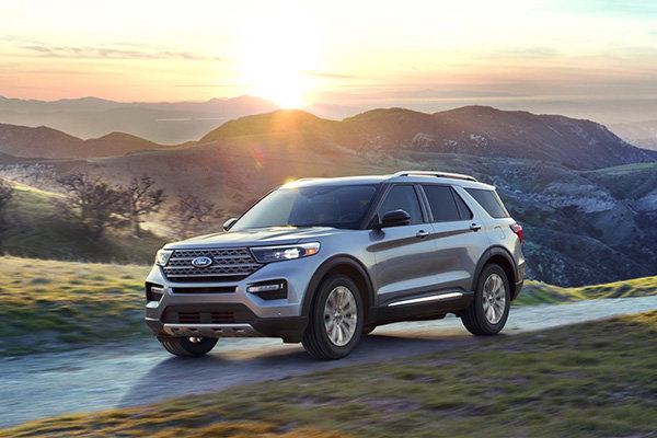 Ford SUV driving on a rural mountain road with sun shining in the background