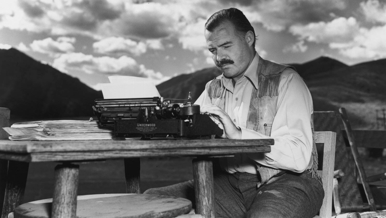 7th October 1939:  EXCLUSIVE American writer Ernest Hemingway (1899 - 1961) works at his typewriter while sitting outdoors, Idaho. Hemingway disapproved of this photograph saying, 'I don't work like this.'  (Photo by Lloyd Arnold/Hulton Archive/Getty Images)