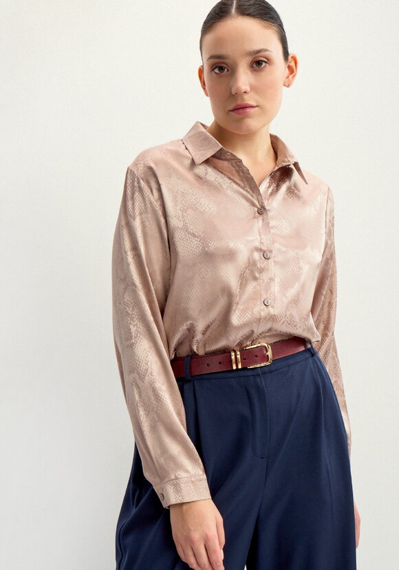 Woman wearing rose-gold satin blouse with navy trousers